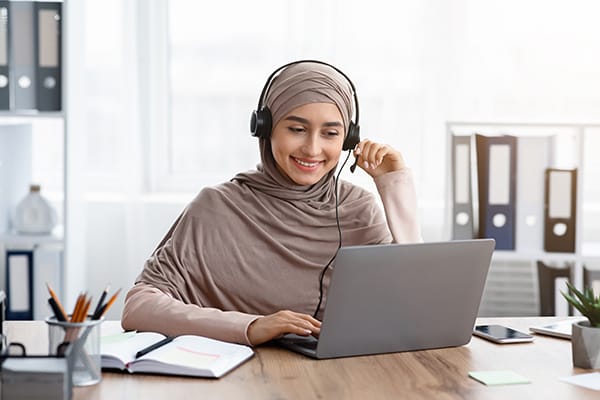 A woman happily conducts business while at her computer.