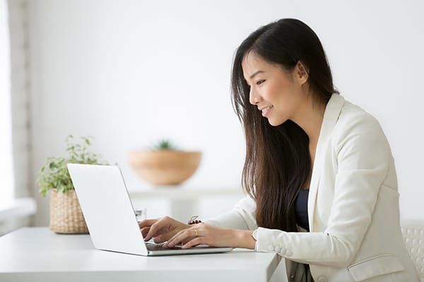 A woman happily conducts business while at her computer.