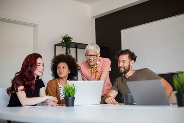 A photo of different generations happily working together around a computer.