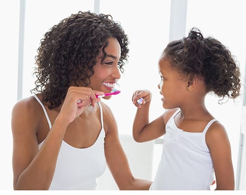 A mother and daughter brushing their teeth together.
