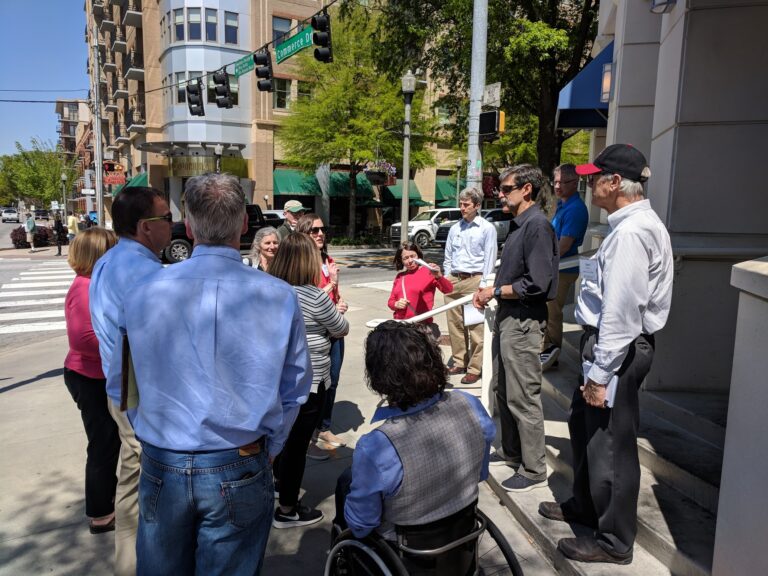 Participants of the 2018 Walkability Action Institute stand on a street corner to examine walkability.