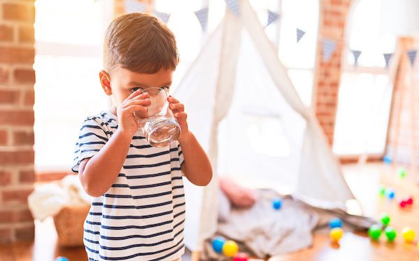 A young child drinks water from a glass