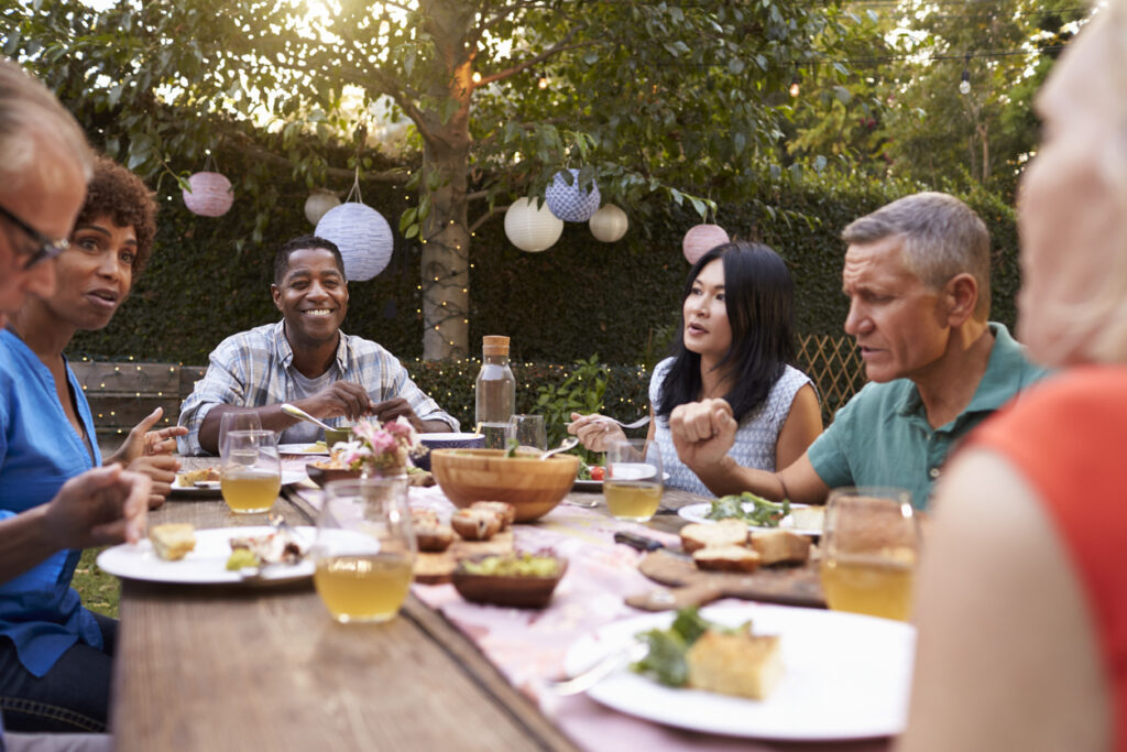 A diverse Group Of Mature Friends Enjoy an Outdoor Meal In the Backyard