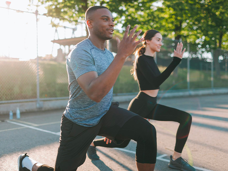 Two people kneeling at dawn doing a fitness together exercise at a park.