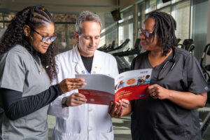 Three medical professionals reviewing the Cardiac Rehabilitation Change Package (CRCP).