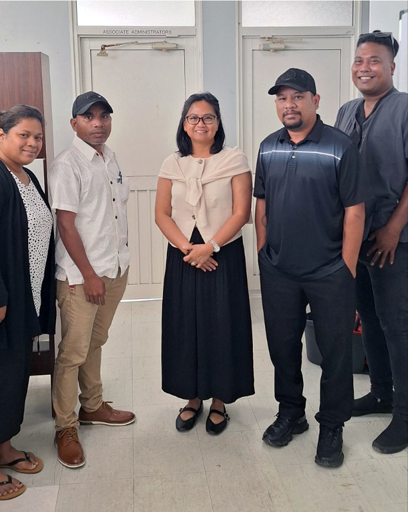 A group of five people stand together inside a building