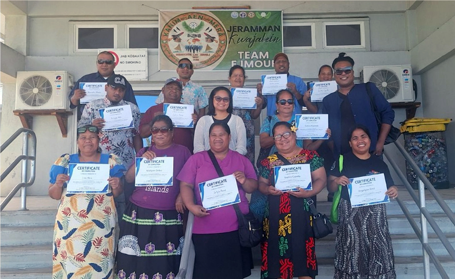A group of people hold certificates and smile