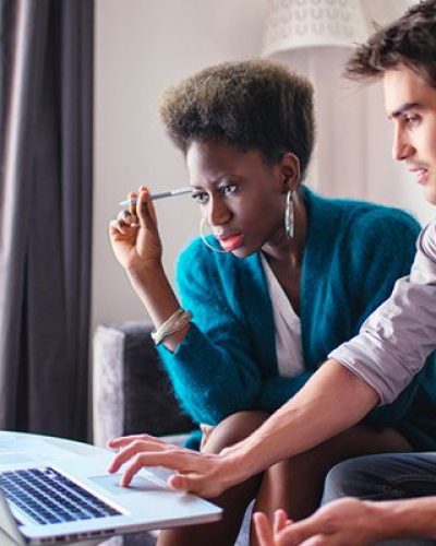 Two young people focused and working on a laptop together.