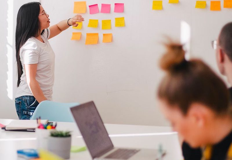 Woman leading a meeting with colorful notes on the wall.