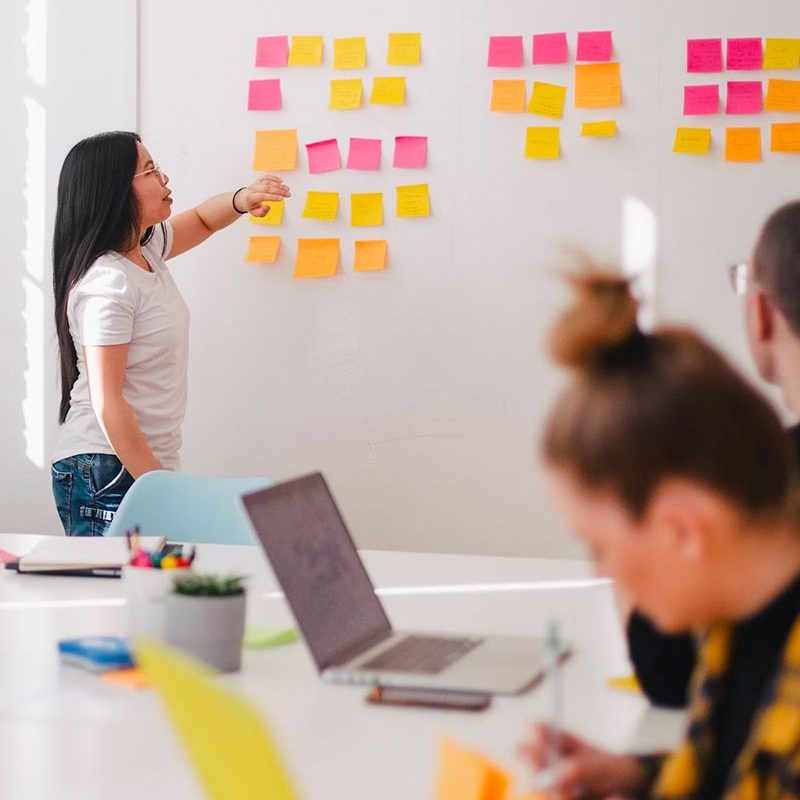 Woman leading a meeting with colorful notes on the wall.
