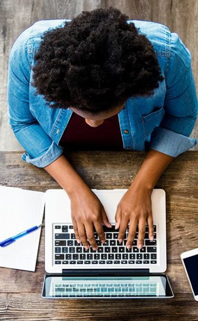 A perspective from above of a person on a laptop with rustic wood textures around.